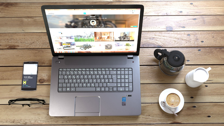 Laptop on desk with coffee, phone, glasses
