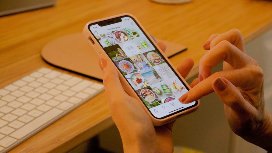 Woman looking at Instagram on phone while sitting at a desk